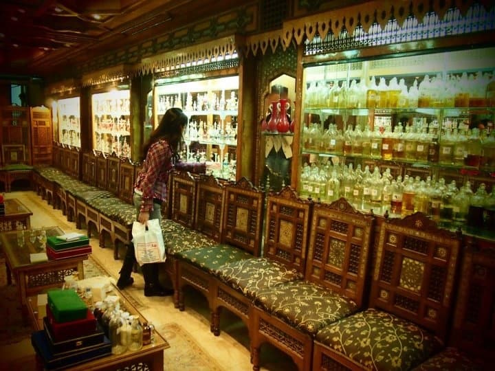 A traveler browsing shelves of traditional Egyptian perfume oils in a wood-panelled Cairo attar shop