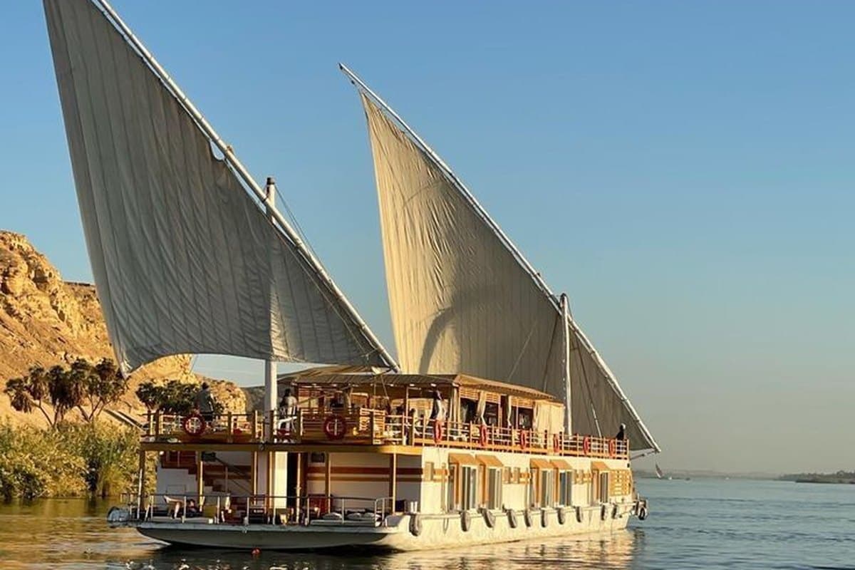 A traditional two-masted dahabiya sailboat under full sail on the Nile near Aswan